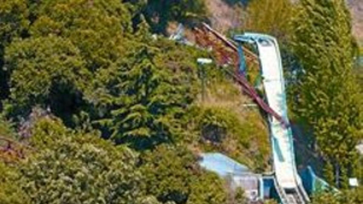 Un grupo de personas en la montaña rusa, frente a 'El Péndulo' caído.