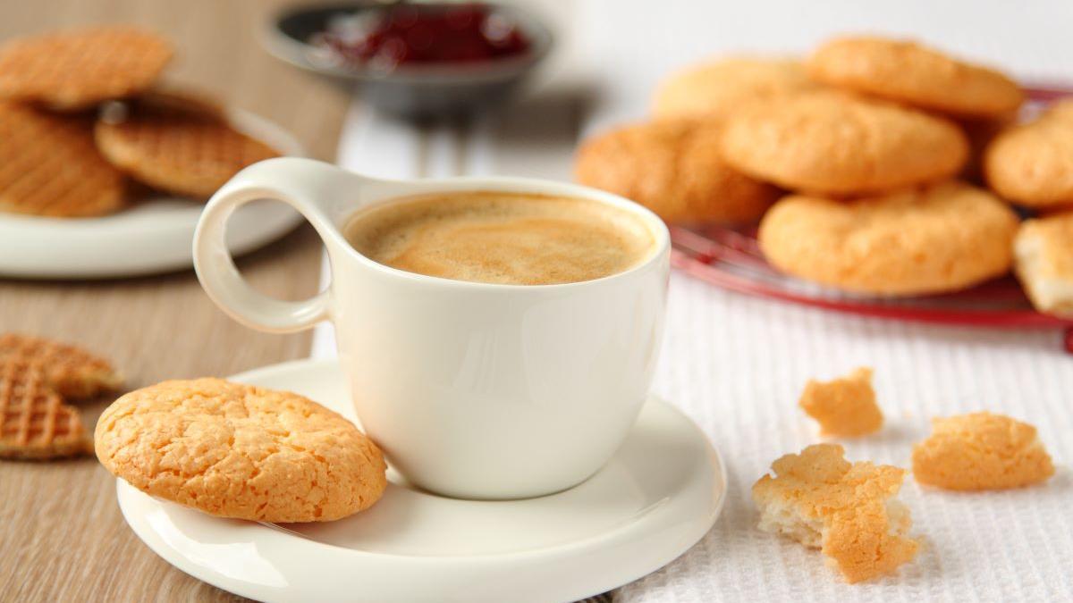 Una taza de café con leche y galletas.