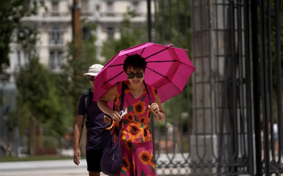Una mujer pasea protegiéndose del sol con un paraguas, el martes en Madrid.
