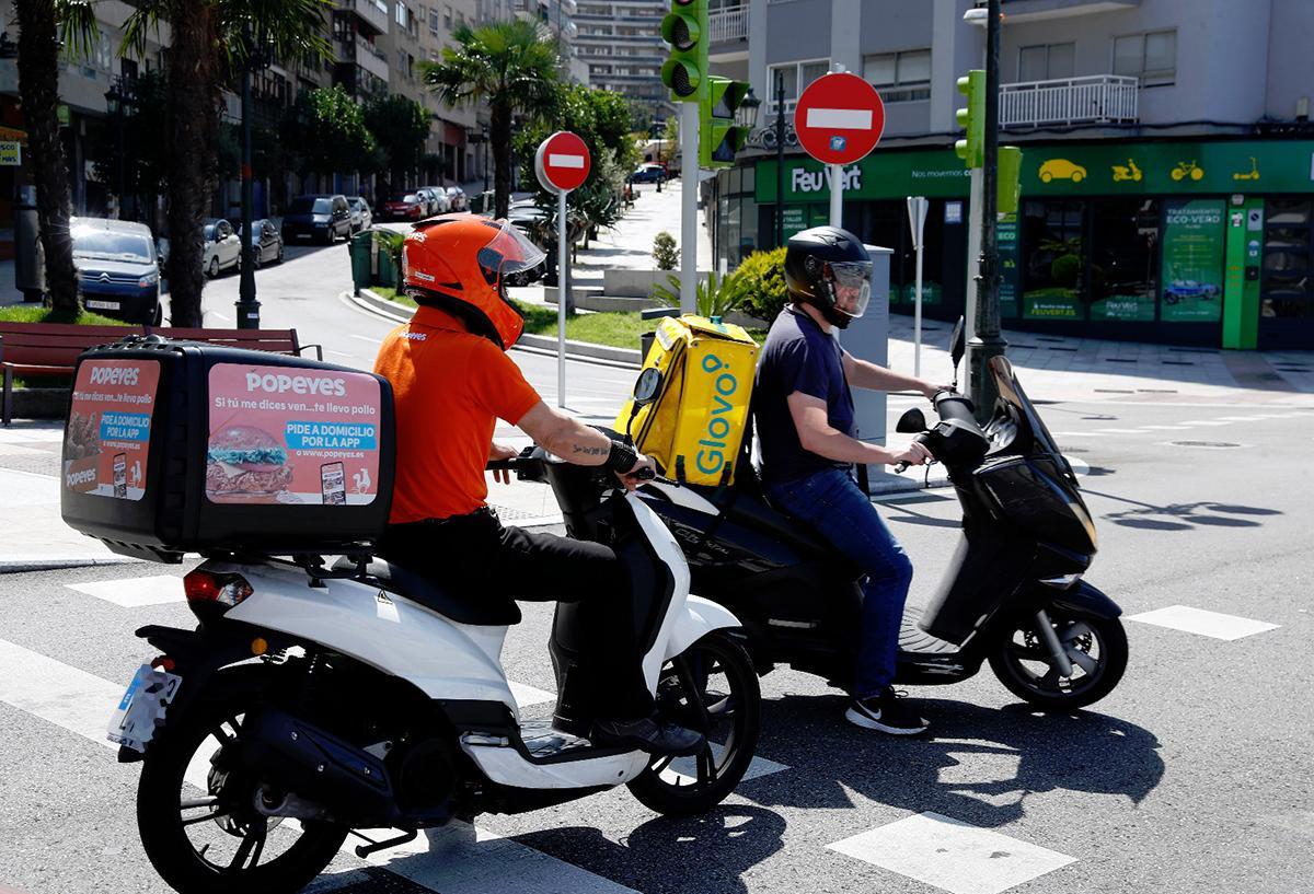 Dos jóvenes repartidores circulan por las calles de Vigo