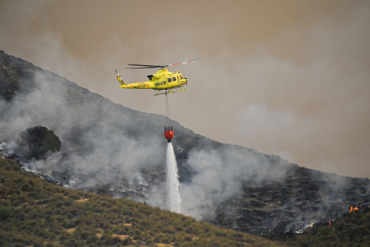 Un helicóptero del servicio de extinción de incendios arroja este viernes agua sobre uno de los focos del incendio forestal declarado en Los Gallardos, Almería.