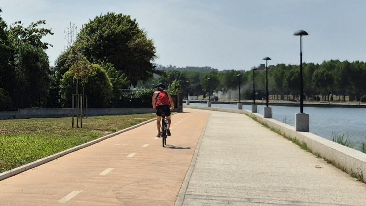 Un ciclista pasea por el carril bici del paseo de la ría en Oleiros.