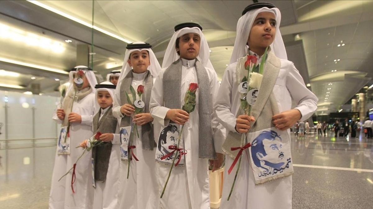 Niños qatarís con flores e imágenes del emir Al Thani reciben a ciudadanos de Kuwait y Omán, países que no se han sumado al boicot, en el aeropuerto de Doha