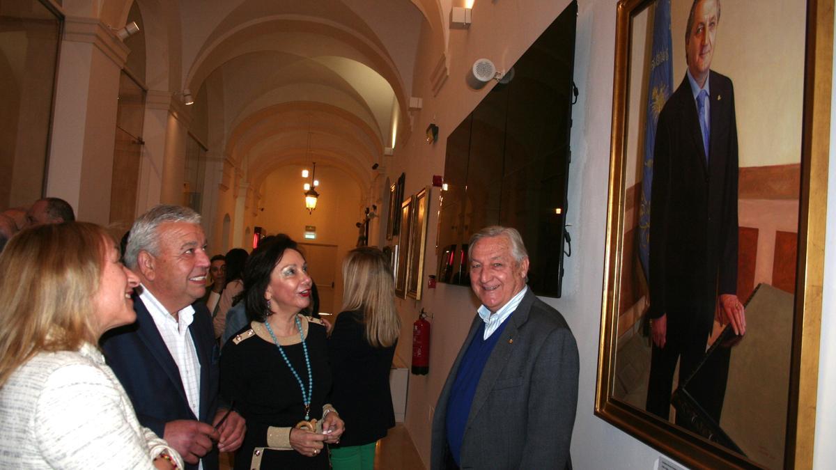 La edil de Cultura, el presidente del Paso Azul y la presidenta de la Asociación de Nuestra Señora la Virgen de los Dolores, contemplan el retrato del Presidente de Honor Cristóbal Alcolea que se mostraba junto al cuadro.