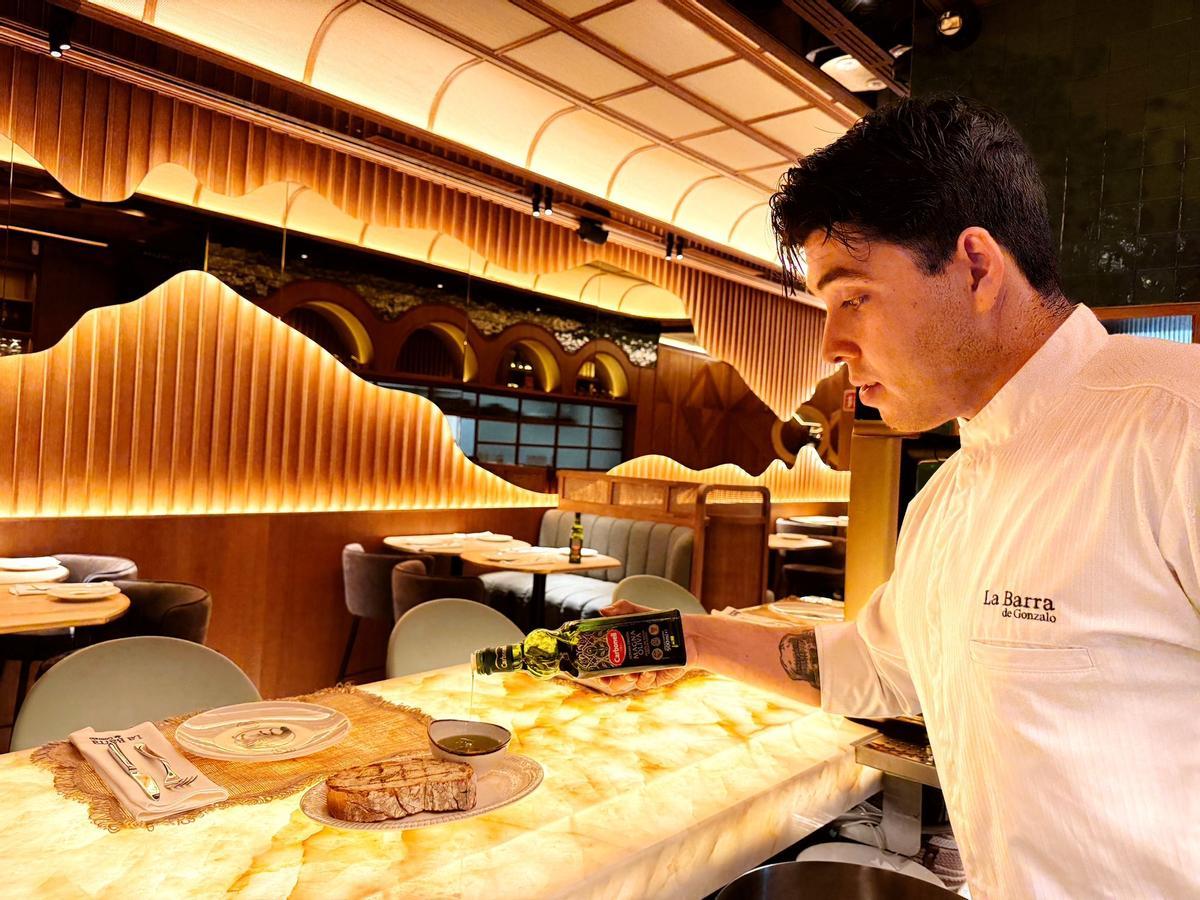 Un camarero sirviendo aceite de oliva virgen extra Carbonell Magna Oliva.