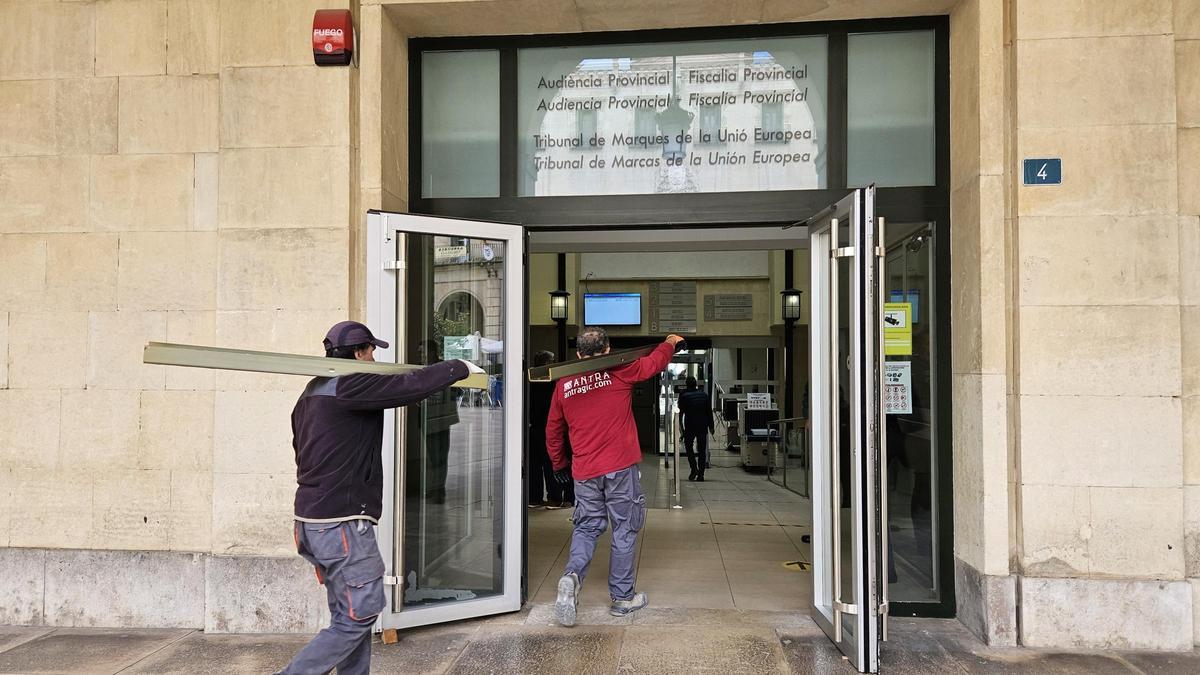 Dos operarios entran este martes en la Audiencia con las vigas de refuerzo.