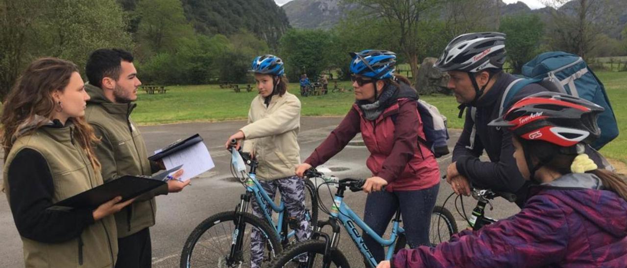 Dos informadores de la Fundación Oso de Asturias asesoran a turistas en bicicleta. | Sara Arias