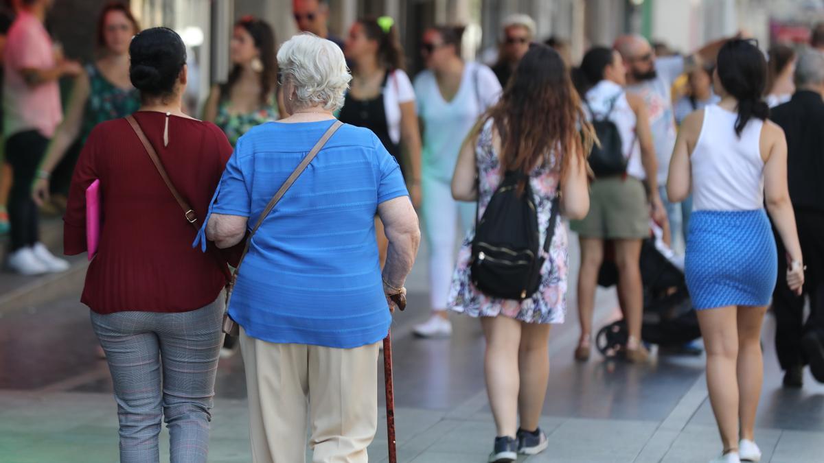 Varias personas pasean por una calle.