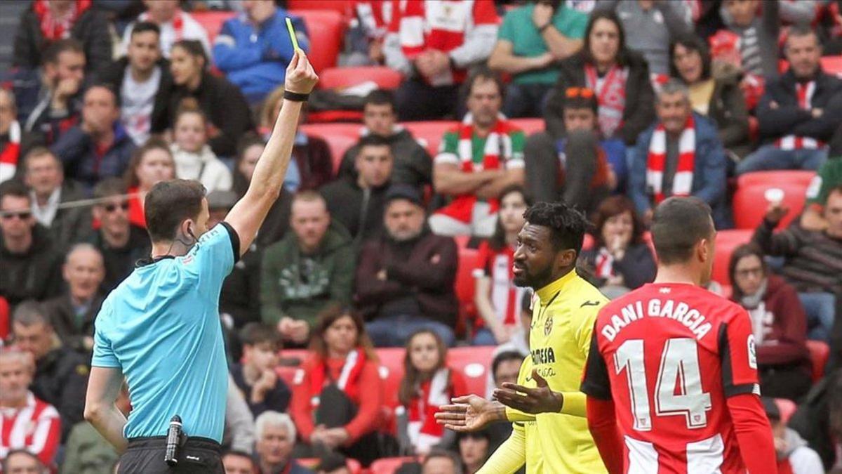 El árbitro David Medié muestra la tarjeta amarilla al centrocampista Zambo Anguissa