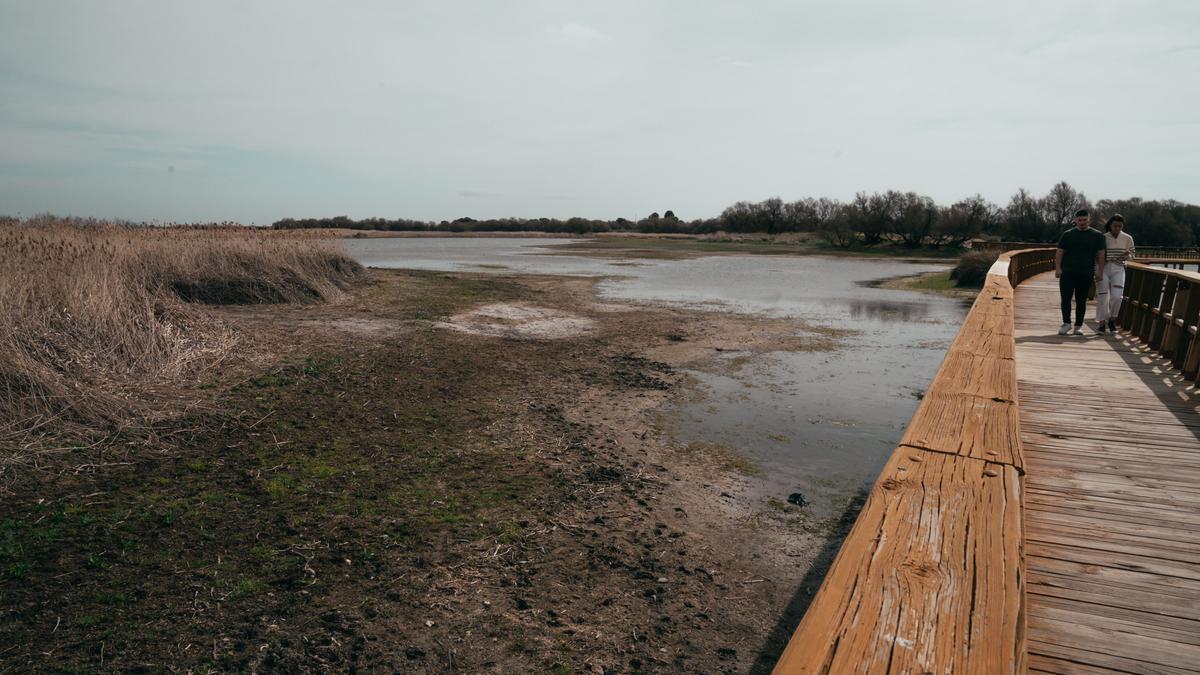 Dos turistas pasan por una de las lagunas casi seca del todo del humedal de Las Tablas de Daimiel.