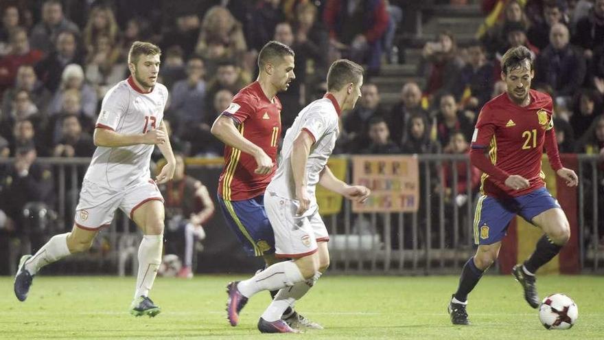 David Silva conduce el balón ante dos defensores de Macedonia y su compañero Vitolo, ayer, en el partido disputado en Granada. // Miguel Ángel Molina