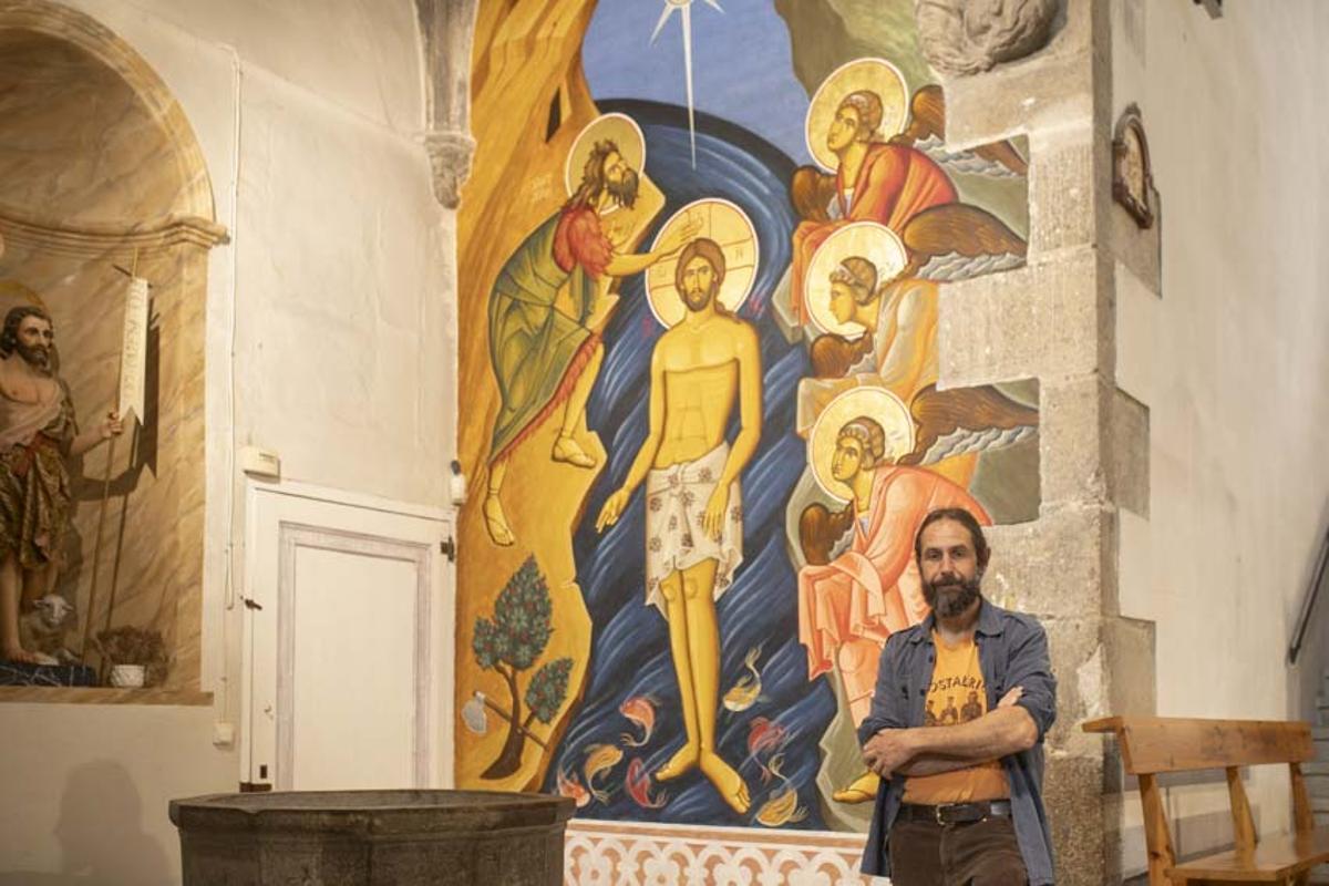 Juan Carlos Osuna, davant del mural que representa el baptisme de Jesús.