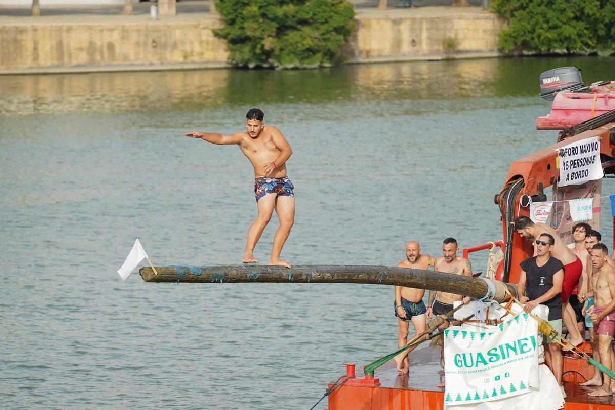 La 'cucaña', el juego centenario que regresa cada verano al río Guadalquivir por la Velá de Santa Ana en imágenes