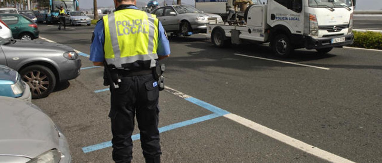 Un policía local ordena la retirada de un vehículo por la grúa municipal en la Avenida Marítima