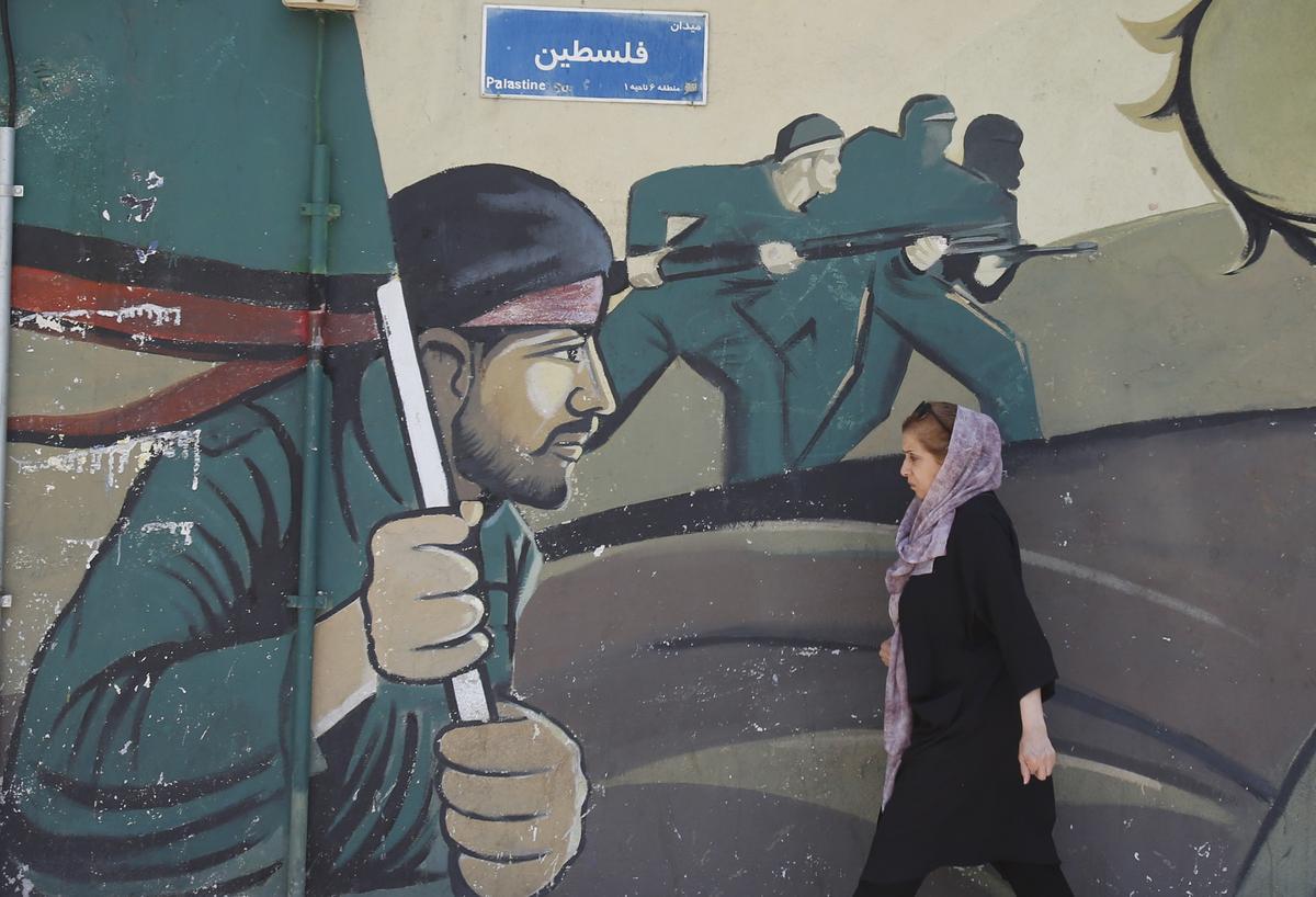 Teherán, Irán 14/04/2024.- Una mujer iraní camina junto a una pintura de la Guardia Revolucionaria Iraní (IRGC) 
