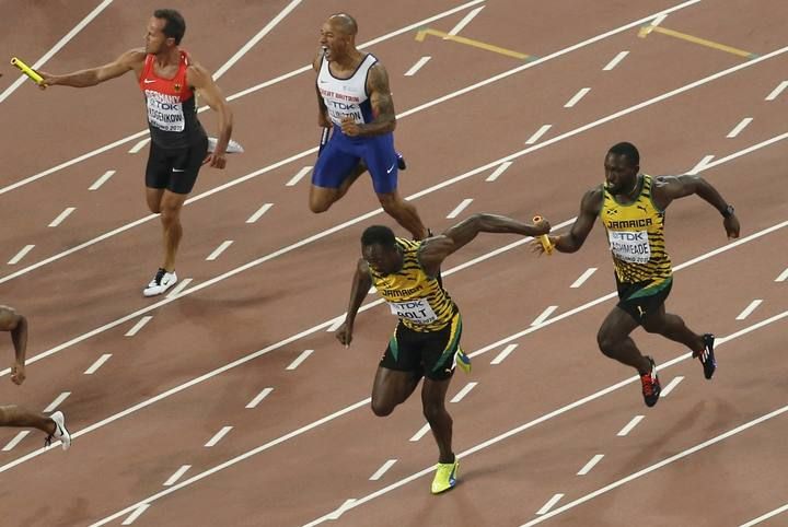 Bolt of Jamaica receives the baton from teammate Ashmeade as they compete in the men's 4 x 100 metres relay final during the 15th IAAF World Championships at the National Stadium in Beijing