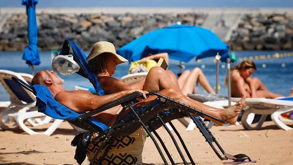 Dues persones gaudeixen del descans a la platja.