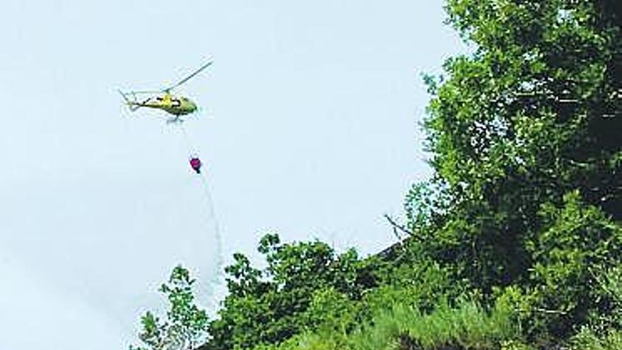 Un helicóptero vierte agua sobre la zona destruida por el fuego.