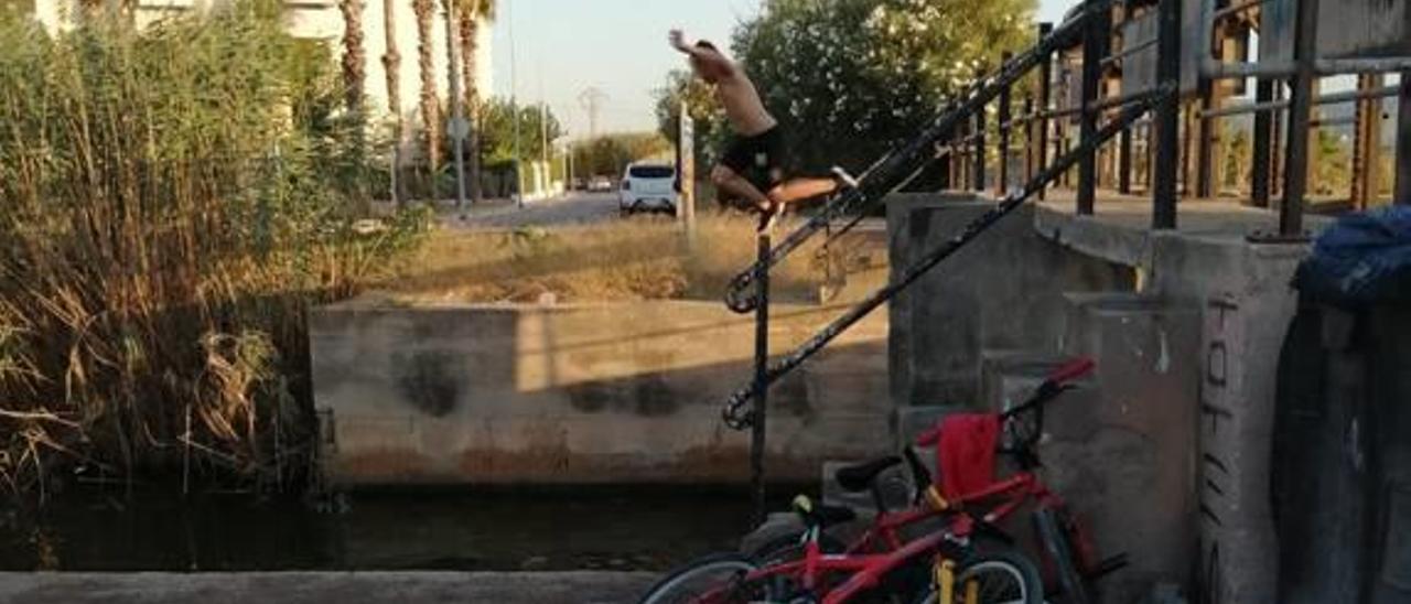 Un menor salta al agua desde las compuertas.