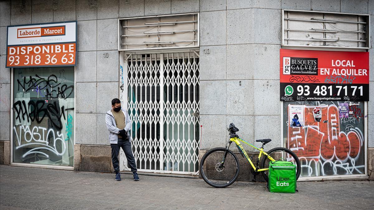 Un repartidor de comida delante de un establecimiento cerrado, en Barcelona. 