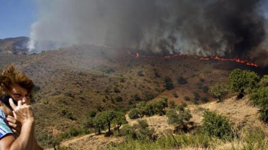 Una vecina de la zona habla por teléfono frente al incendio que se ha declarado esta tarde en el paraje El Mirador, perteneciente a los Montes de Málaga, donde han sido desalojados siete cortijos.