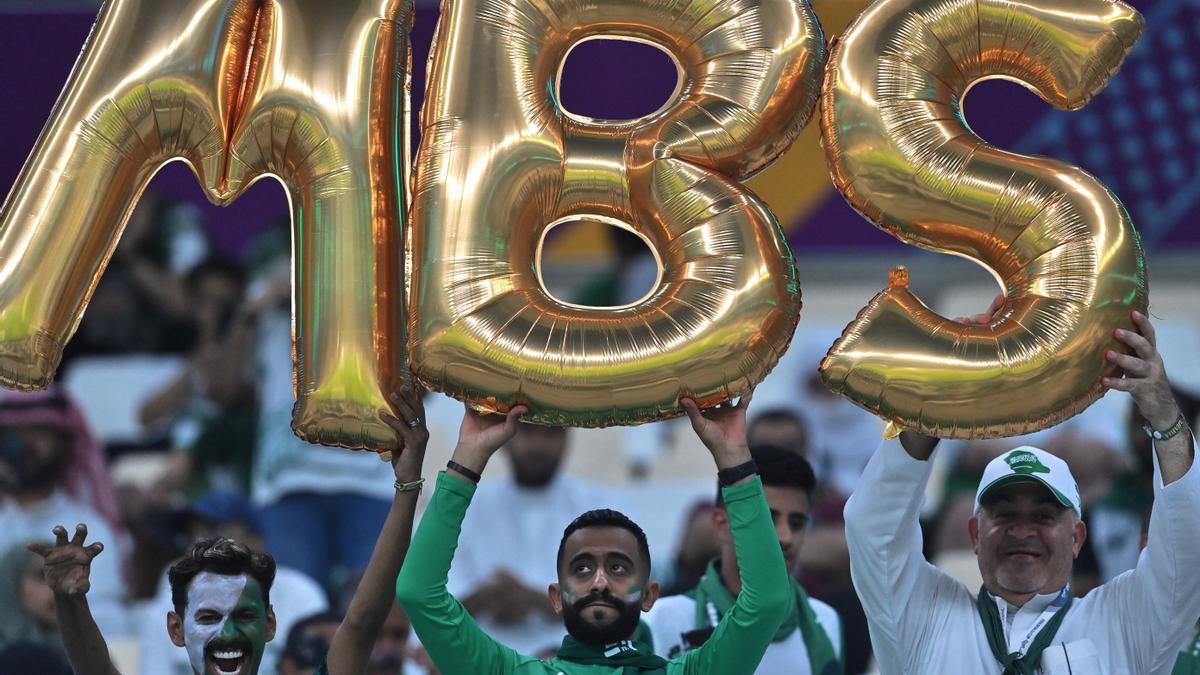 Simpatizantes saudís en el Mundial de Catar sostienen globos con las iniciales del príncipe saudí Mohamed bin Salman.