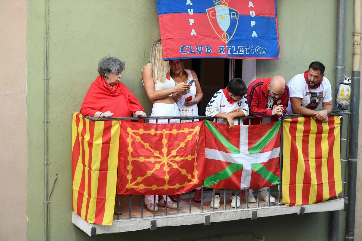 Los residentes observan desde un balcón que exhibe banderas de Cataluña Senyara, una bandera de Navarra y una bandera vasca Ikurrina durante el encierro (corrida de toros) de las fiestas de San Fermín en Pamplona.