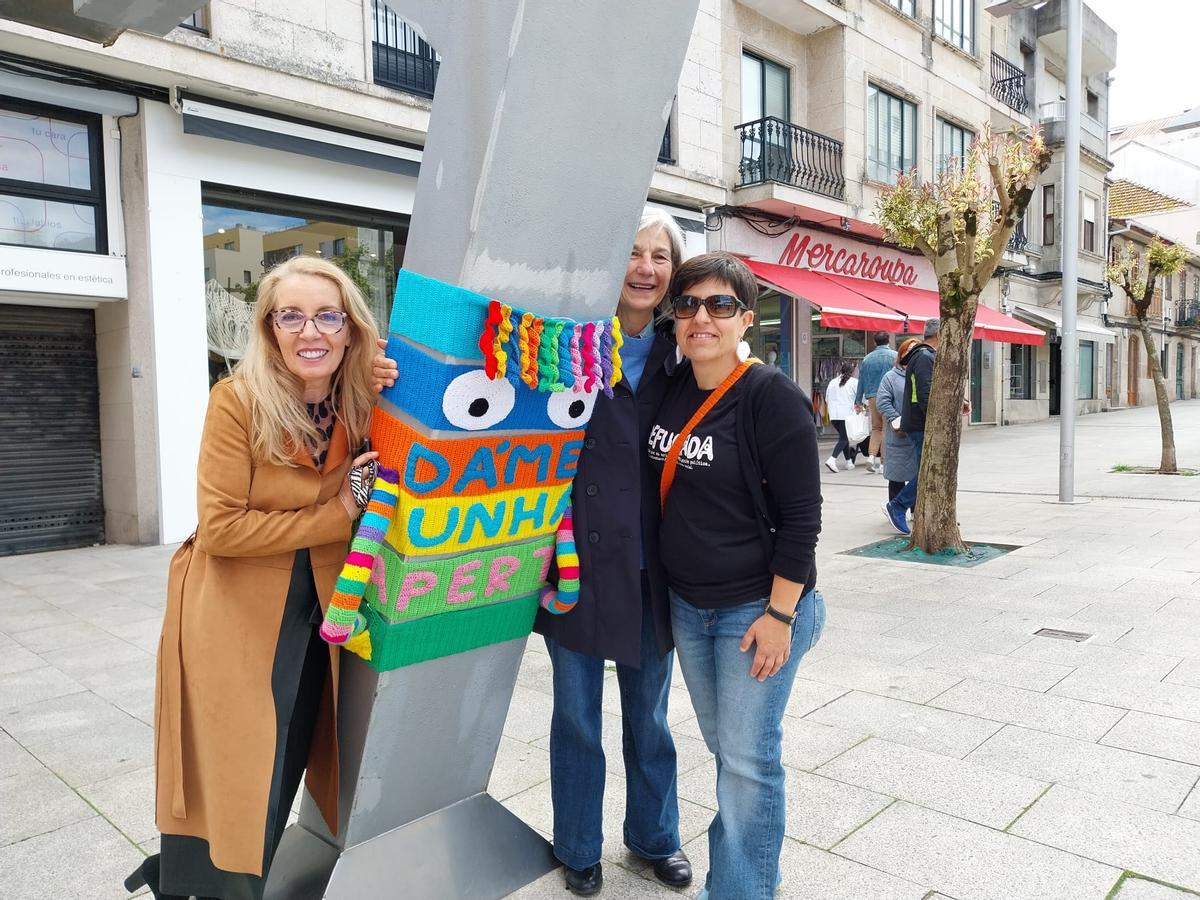 La directora del colegio de Beluso junto a la directora y vicedirectora del IES Johan Carballeira con el "monstruo das apertas" para darle un achuchón.