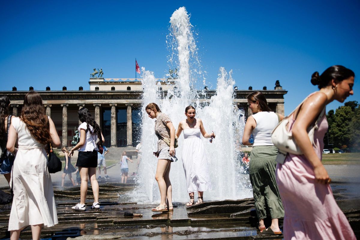 Un grupo de turistas se refresca en una fuente frente al Museo Antiguo de Berlín.
