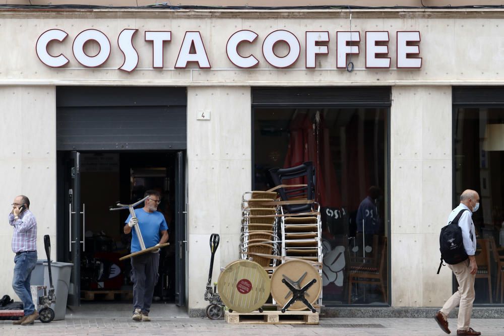 Imágenes de una lluviosa mañana de jueves en el centro de Málaga, donde al paisaje ya habitual de pocas personas y la mayoría de ellas con guantes y mascarillas se le han añadido los preparativos de bares, cafeterías y terrazas que se preparan para el inminente cambio de fase de la desescalada de la ciudad.