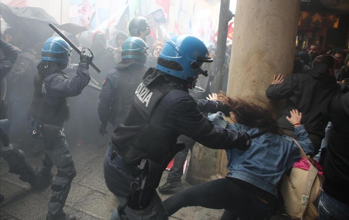 Varios policías cargan contra un grupo de manifestantes durante las protestas contra un mitin electoral del partido de extrema derecha Fuerza Nueva, este lunes en Bolonia (Italia). Los protestantes trataron de romper el cordón policial.