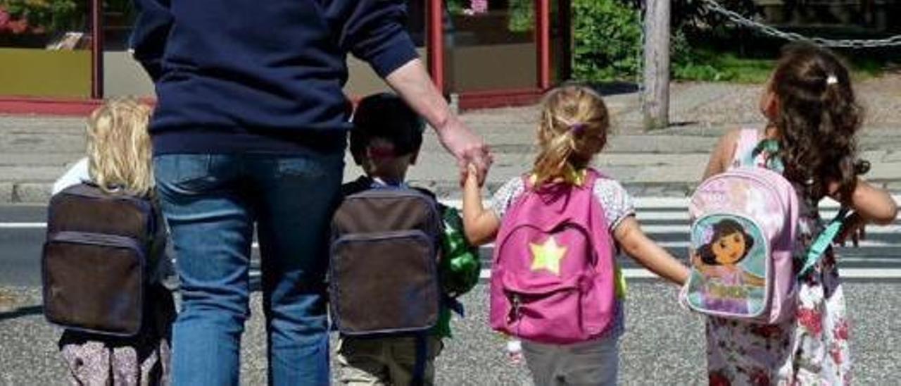 Niños acudiendo al colegio de la mano de una madre.
