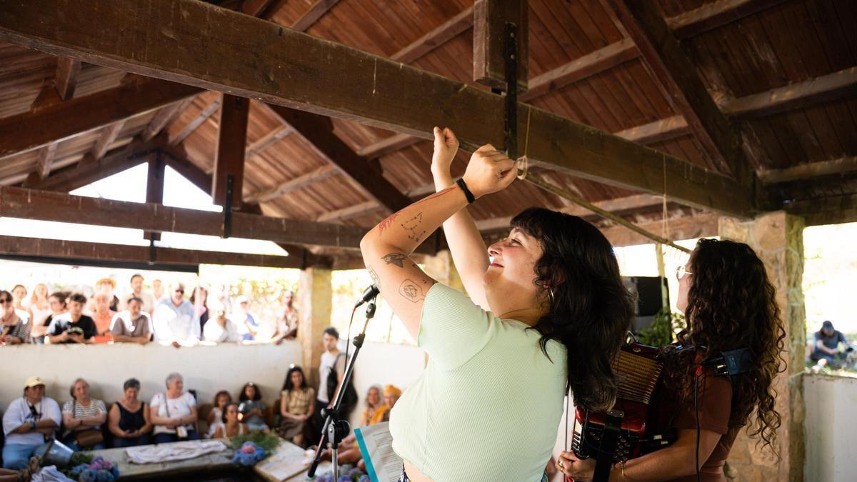 Antía EseUve y Ana Pereda, de espaldas, durante el concierto participativo en la fuente de Las Caldas.