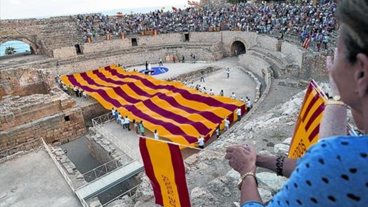 La gran 'senyera' desplegada por Societat Civil Catalana en Tarragona, con una participante que enarbola una bandera española.