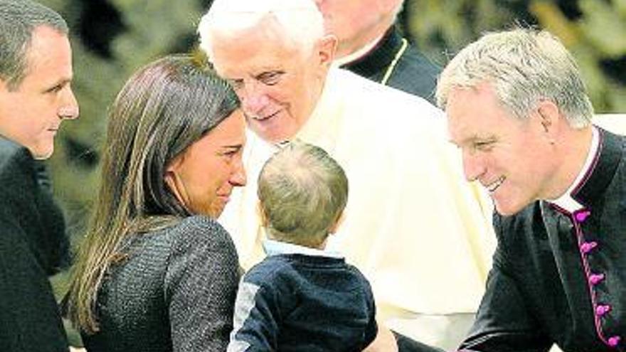 Benedicto XVI y su secretario, Georg Gaenswein, saludan a una familia.