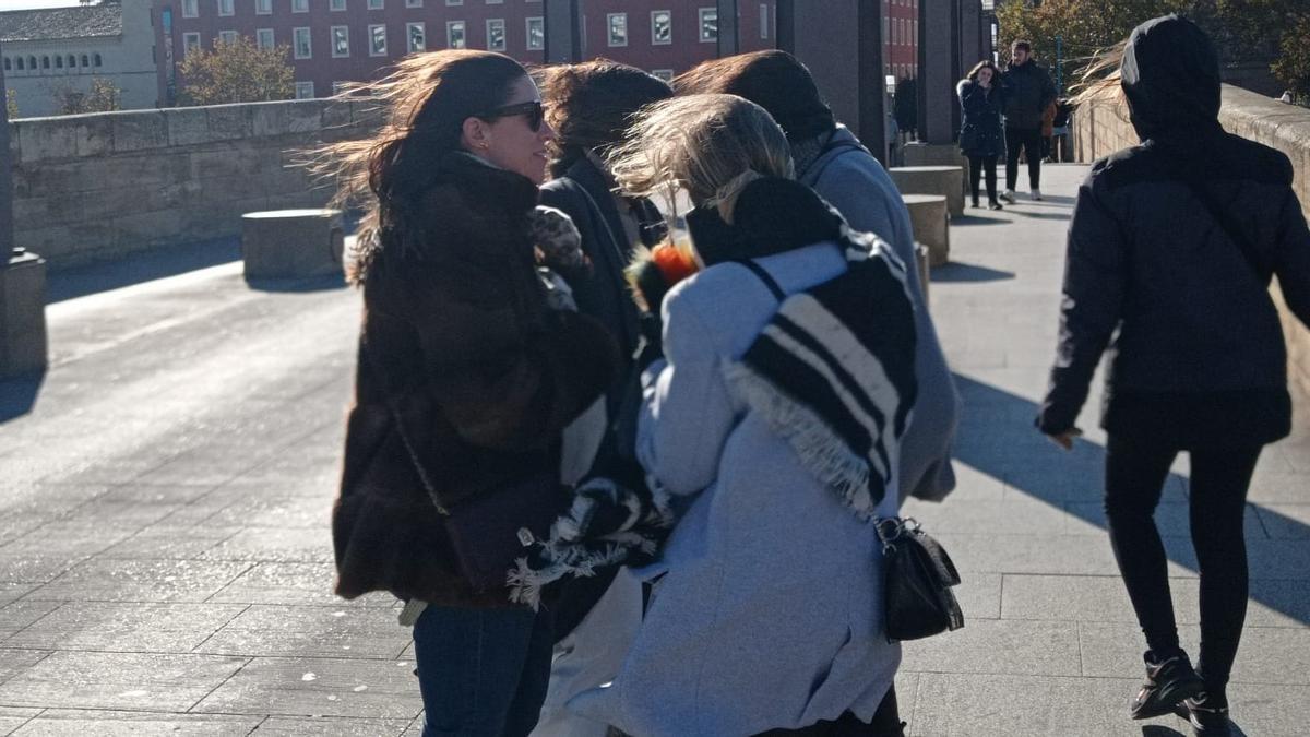 Un grupo de jóvenes se protege del viento en el puente de Piedra