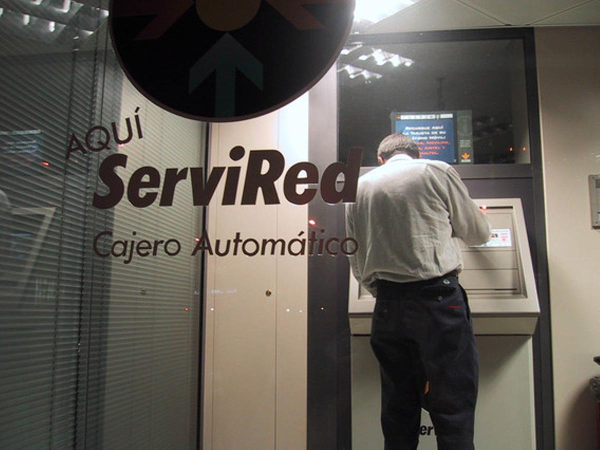 Un home treu diners d’un caixer automàtic de Servired, a Barcelona. Un home treu diners d’un caixer automàtic de Servired, a Barcelona.