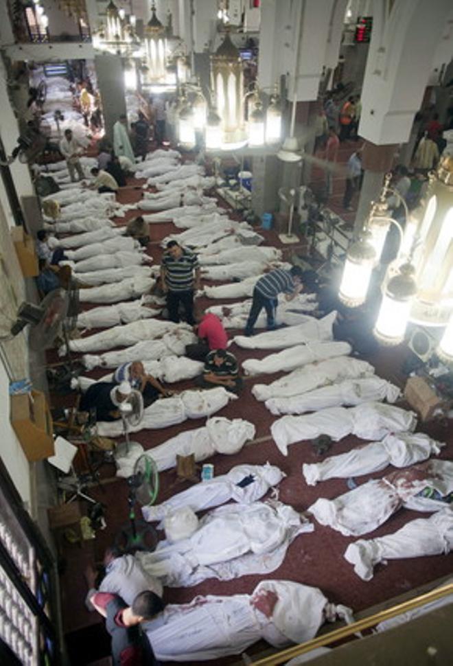 Diverses persones al costat de dotzenes de cadàvers de familiars a la mesquita Al-Imene, al Caire, aquest dijous.