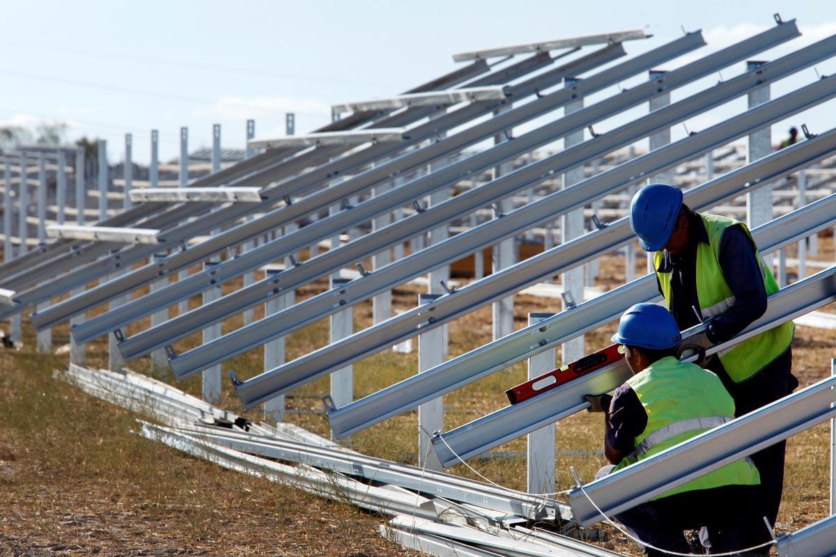 Imagen de archivo de dos operarios instalando paneles solares en una central.