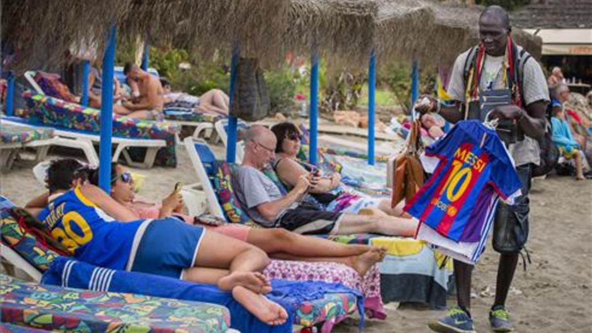 Un joven vende camisetas de Messi en la playa de Benalmádena (Málaga).