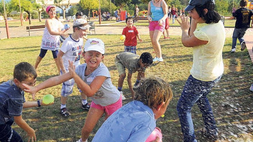 Un instante de la guerra de globos de agua (arriba) e (izda), pequeños en las atracciones instaladas ayer en el parque cruceño.  // Bernabé/Javier Lalín