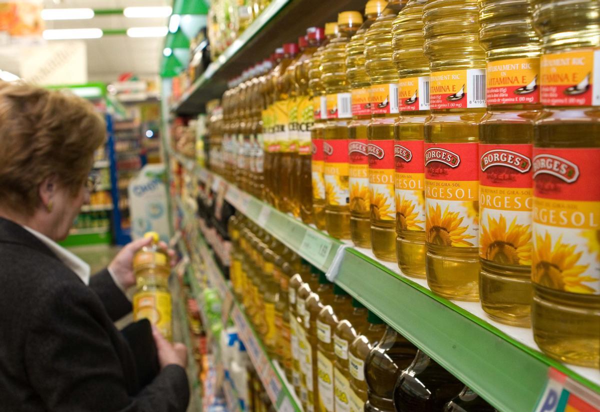 Una mujer coge una botella de aceite de girasol en un supermercado.