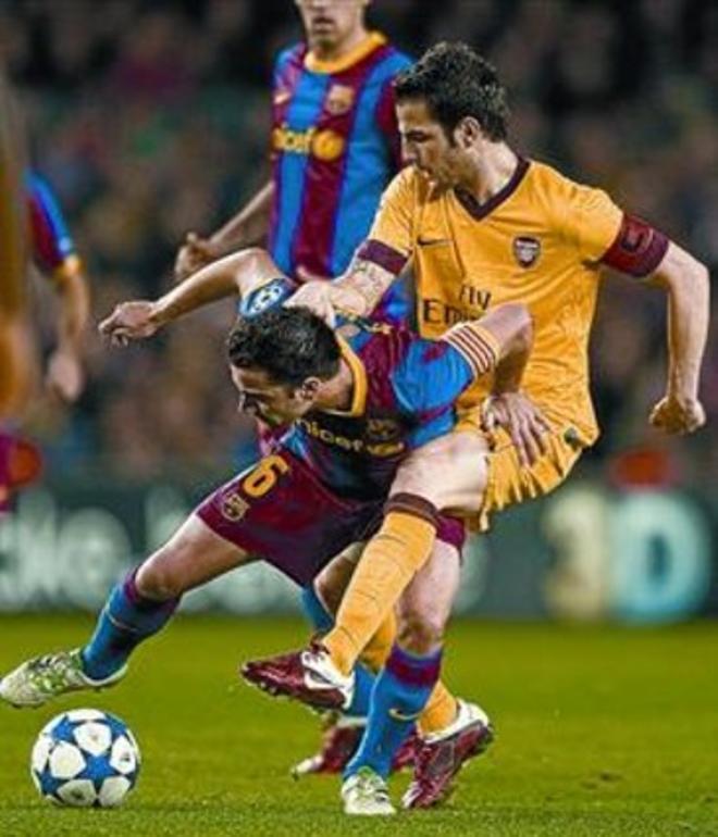 Cesc intenta arrebatar un balón a Xavi, anoche en el Camp Nou.
