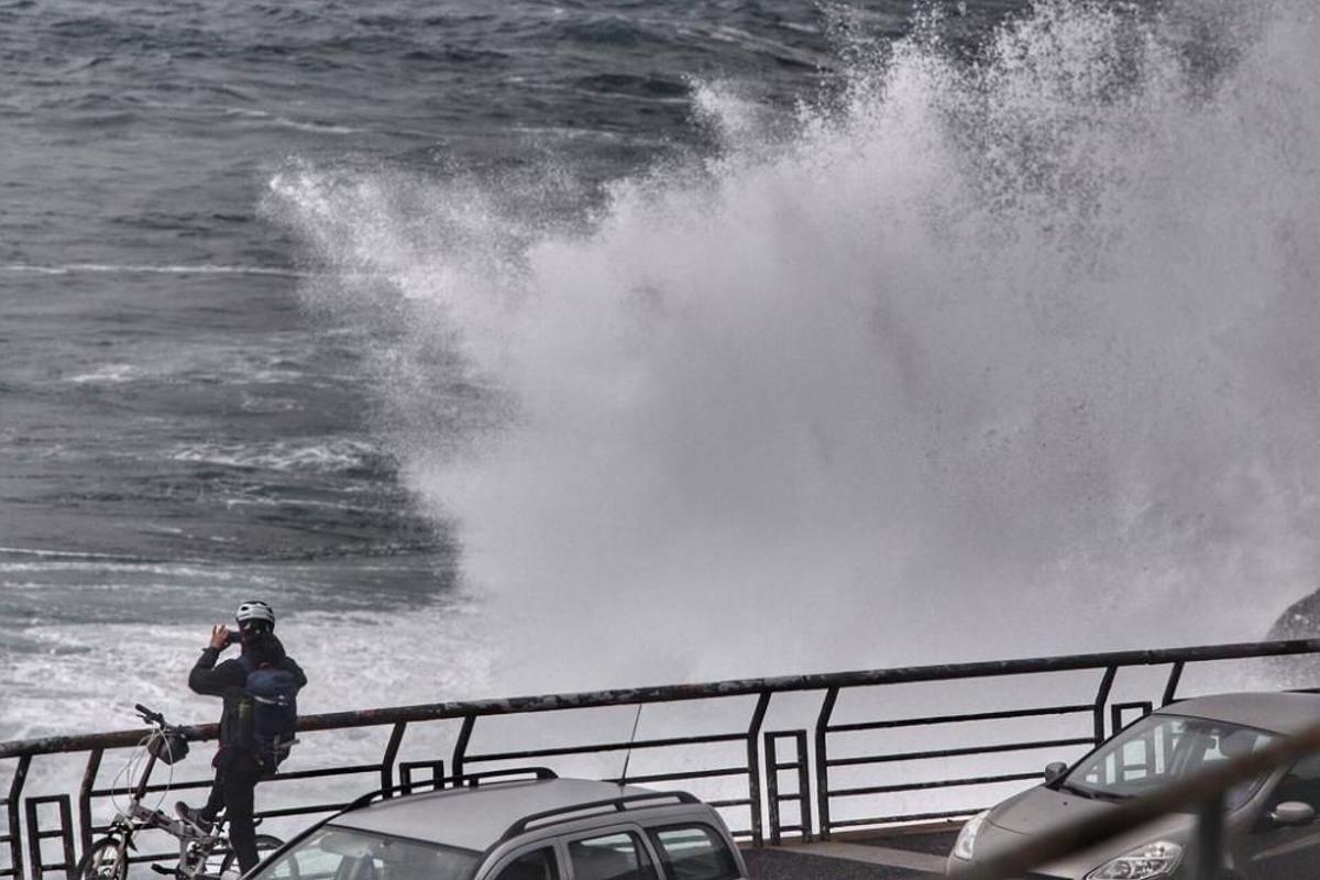 Foto de archivo de un ciclista tomando una foto al fuerte oleaje durante un temporal.