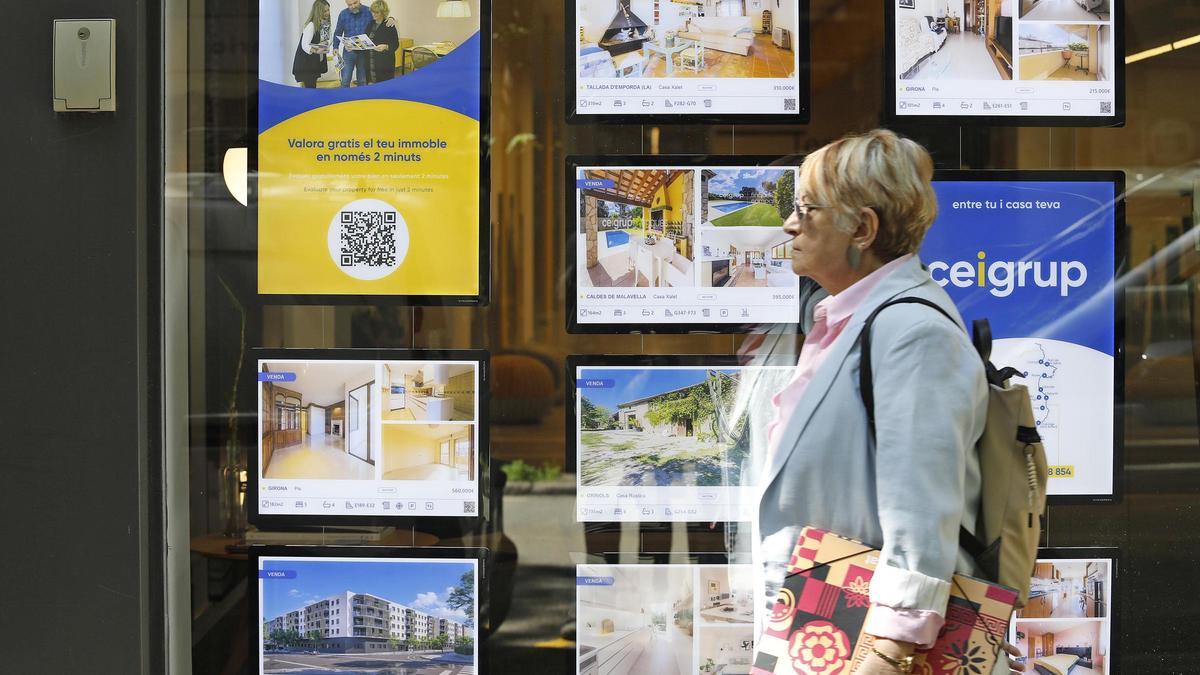 Una dona davant l'aparador d'una immobiliària a Girona.