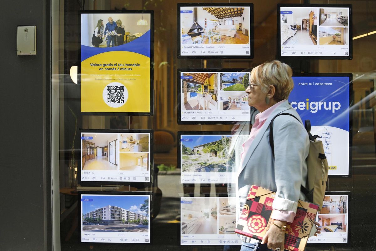 Una dona davant l'aparador d'una immobiliària a Girona.