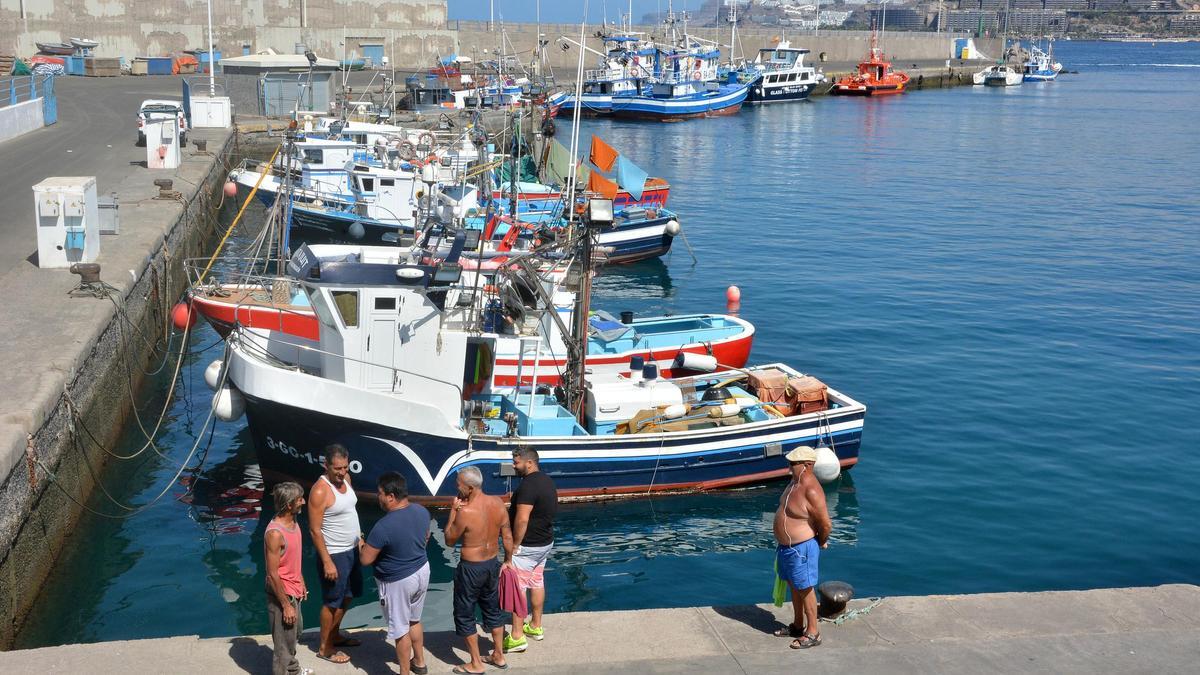 Varios pescadores junto a sus barcos en Arguineguín, Gran Canaria.
