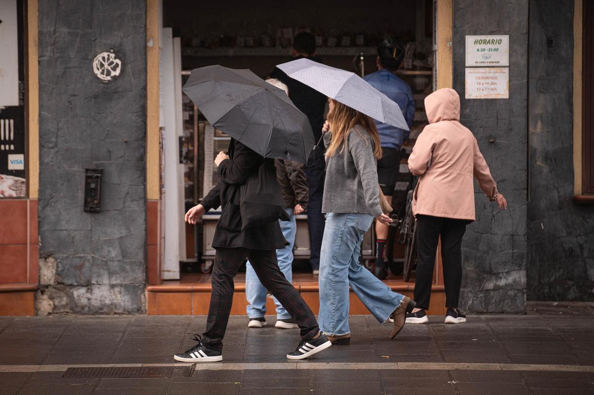 Diferentes personas se protegen de la lluvia en Tenerife.