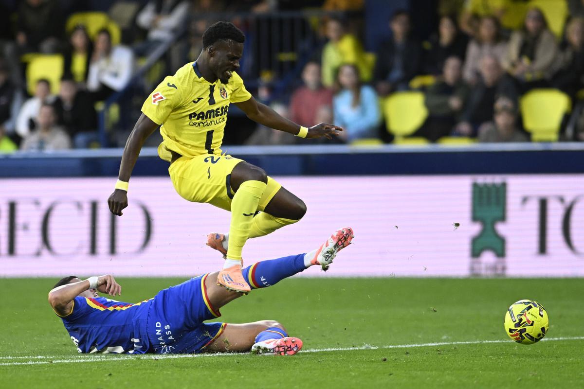 VILA-REAL (CASTELLÓN), 06/12/2025.- Tani Oluwaseyi (c) del VIllarreal, supera a Abdel Abqar, del GEtafe (i) durante el partido de la jornada 13 de LaLiga EA Sports entre el Villarreal y el Getafe, disputado este sábado en el Estadio de la Cerámica de Vila-Real (Castellón). EFE/ Andreu Esteban