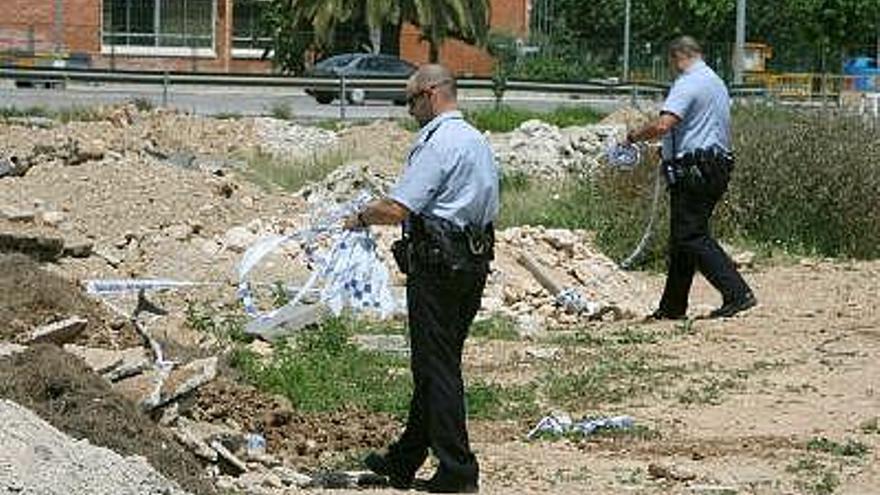 Dos policías municipales retiran la cinta de zona restringida del lugar donde esta mañana han matado a un hombre en Amposta.
